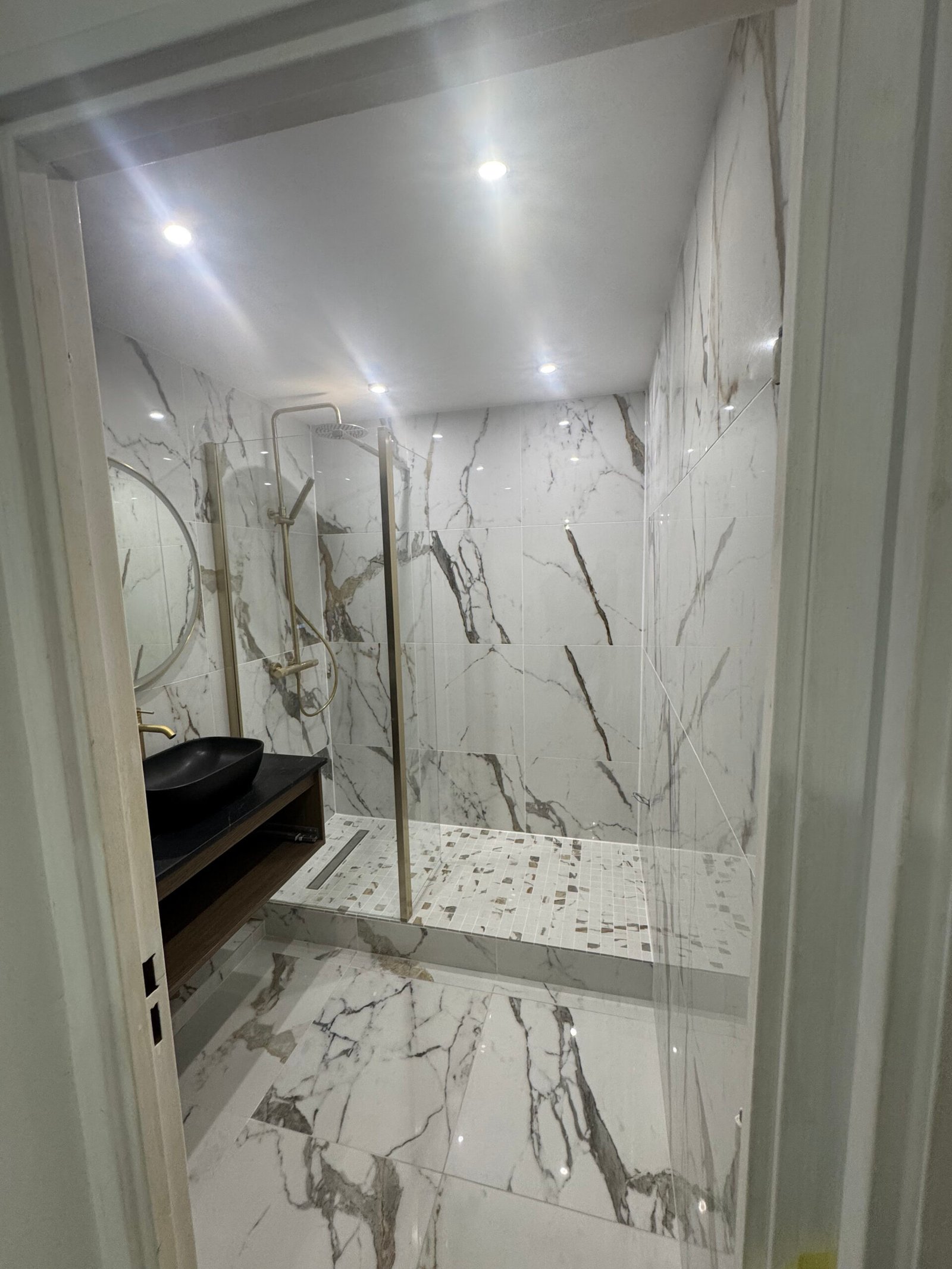 Vue de la salle de bain avec carrelage effet marbre et vasque noire, Paris 15