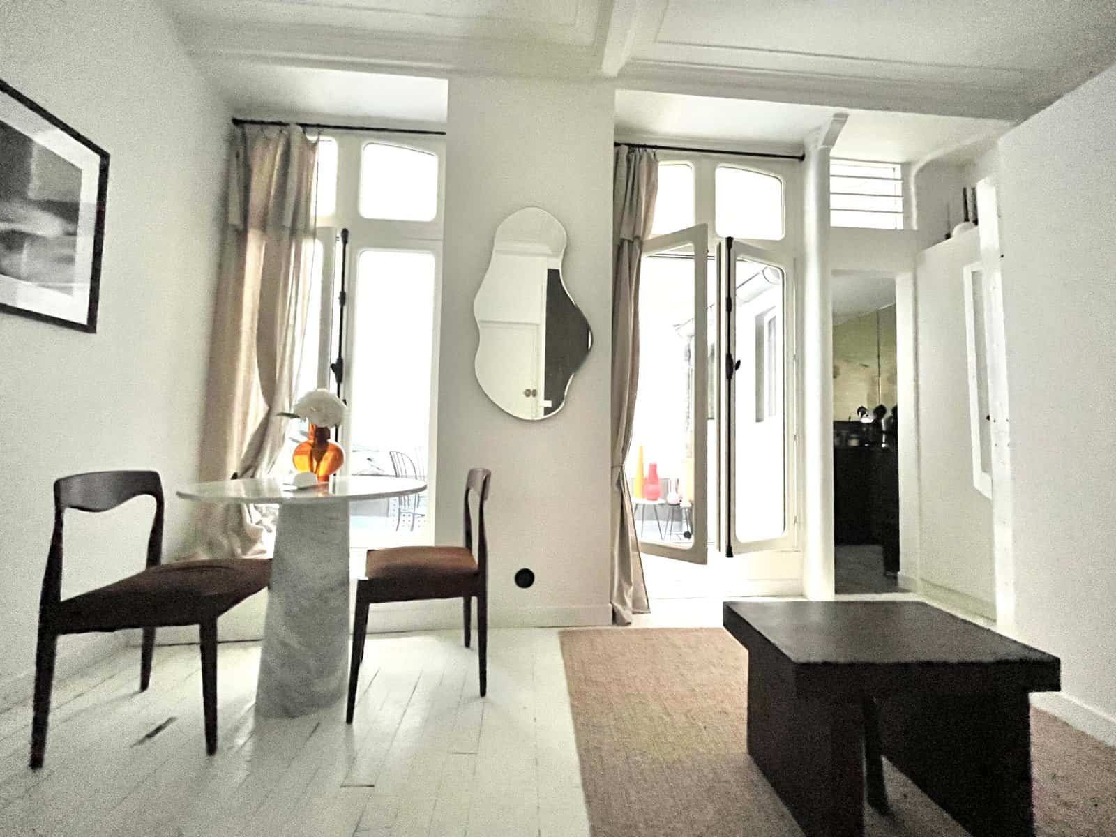 Intérieur d'un appartement lumineux avec balcon et mobilier moderne.