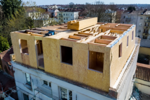 Surélévation d’immeuble en chantier avec extension en ossature bois, toiture en cours de pose et échafaudage par une entreprise de bâtiment