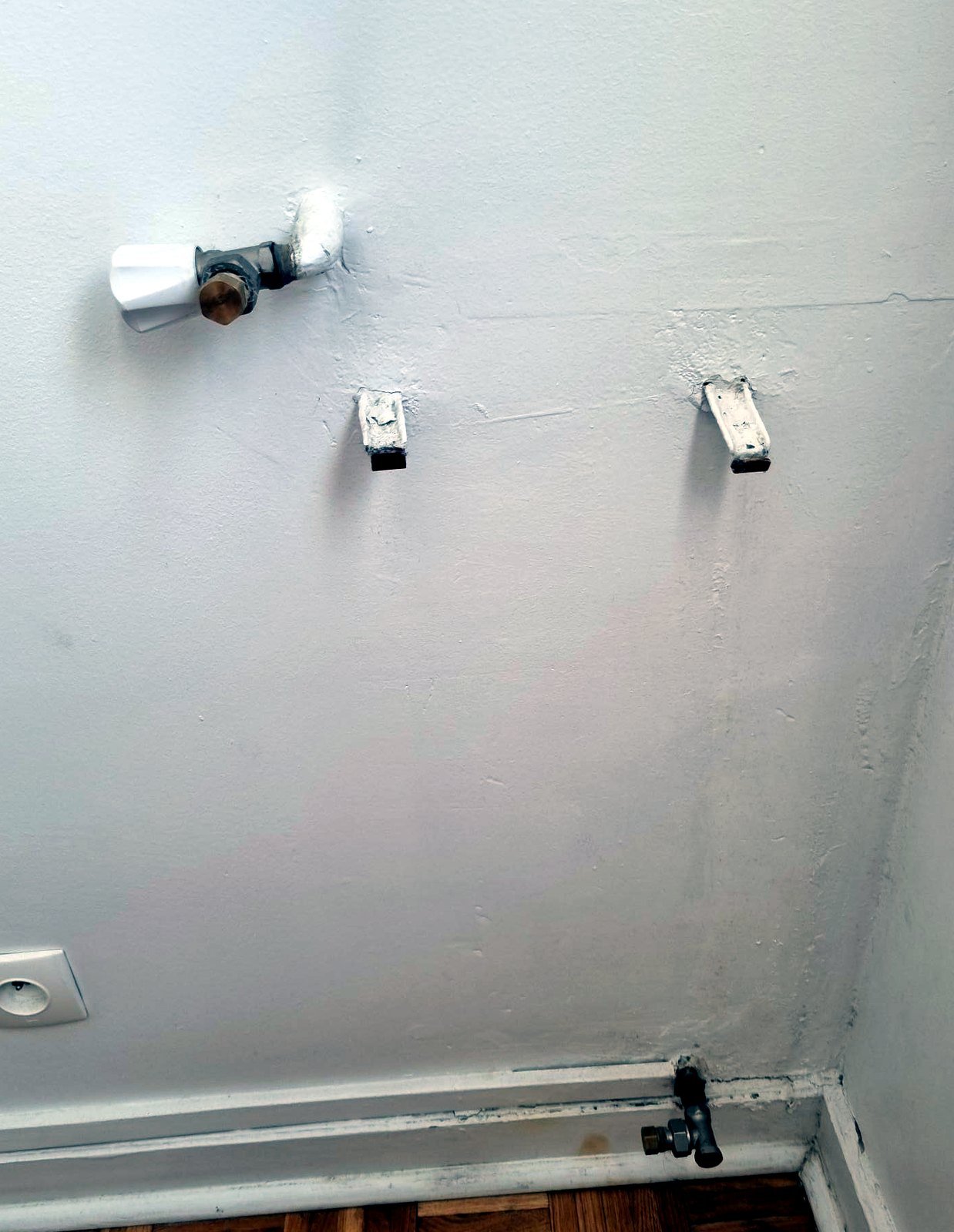 Mur nu après dépose du radiateur, arrivée de chauffage en haut à gauche et consoles de fixation
